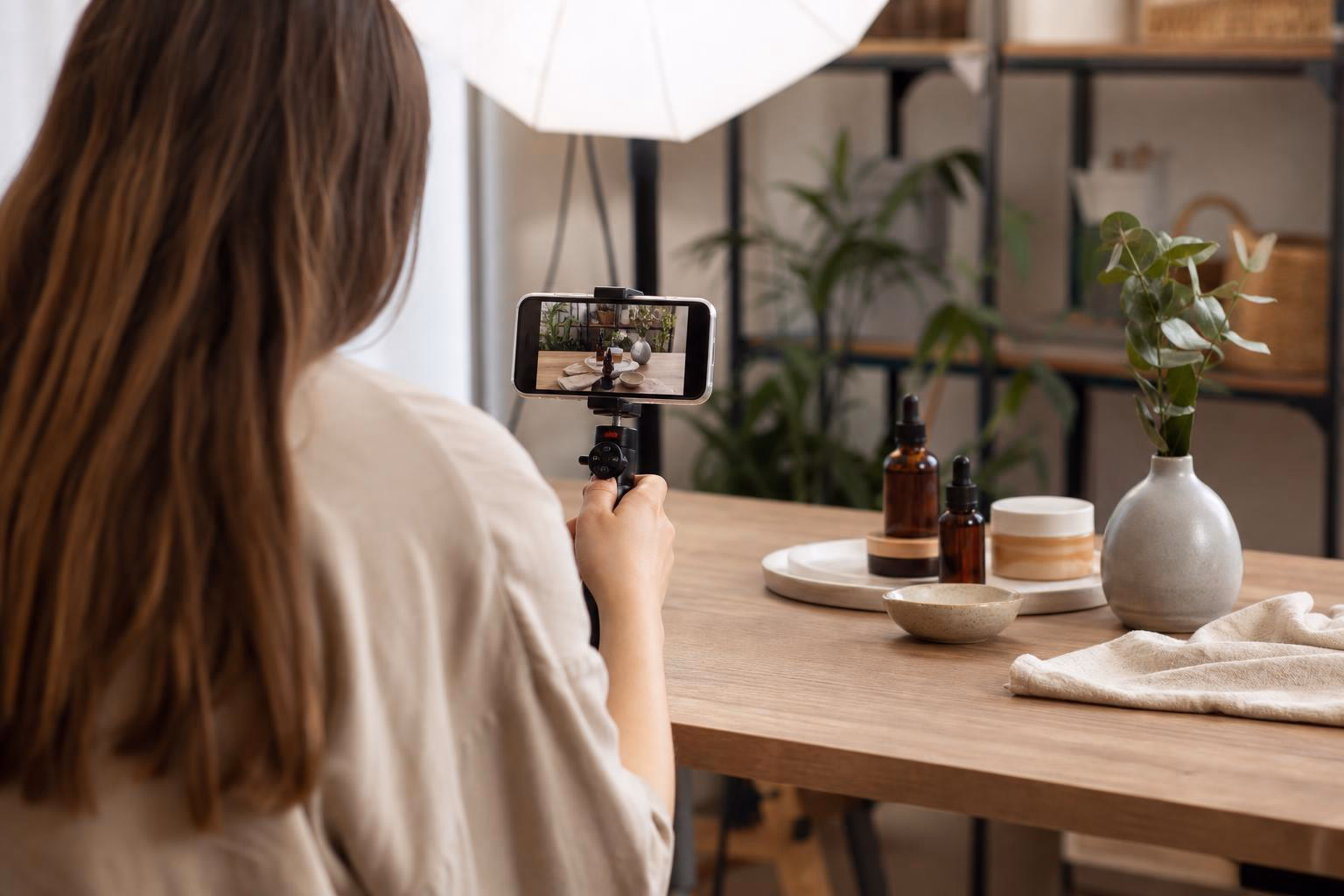 A creator filming product content for Instagram on a tripod-mounted phone under a studio softbox light.