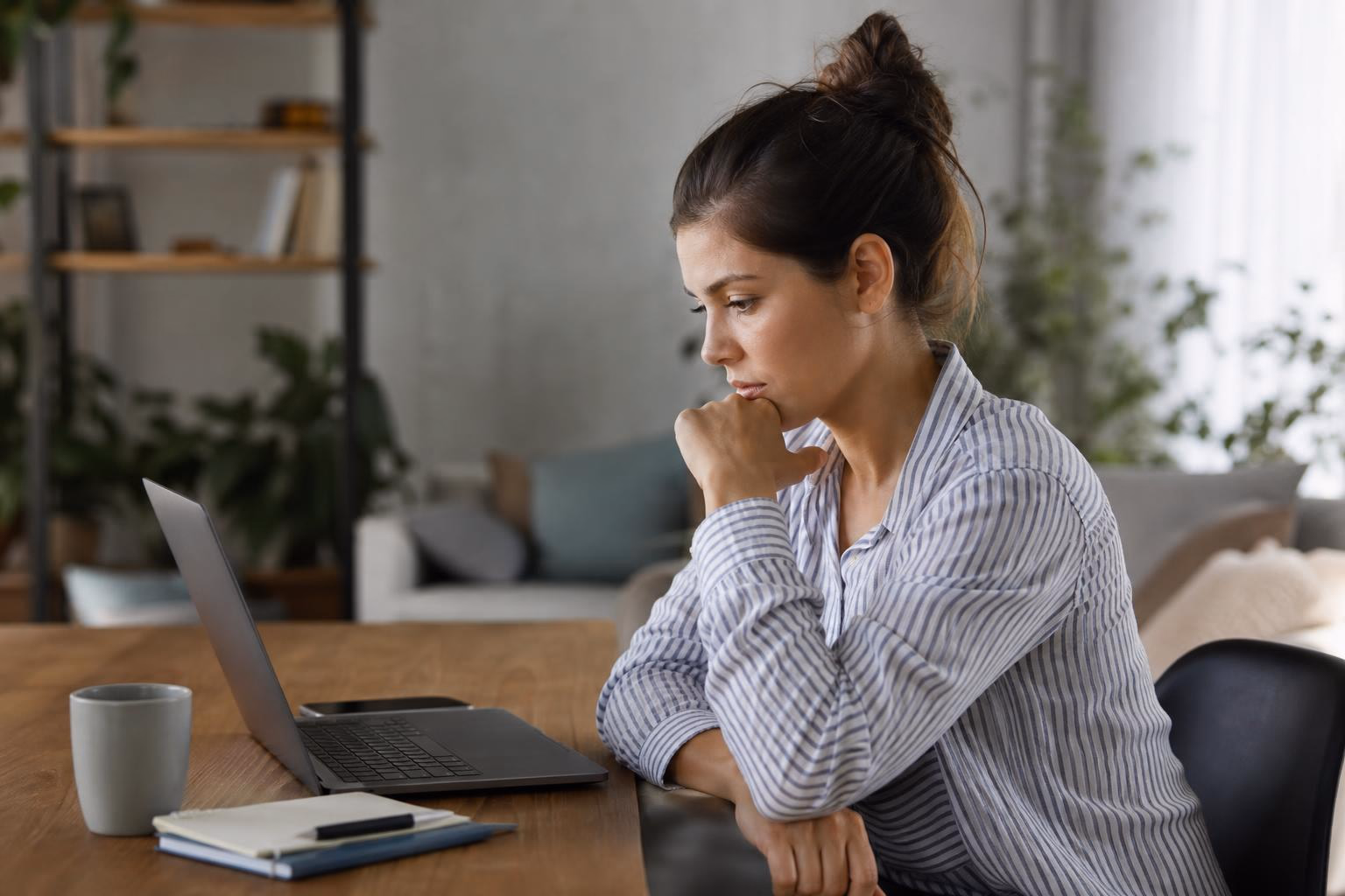 A content creator reviewing text on her laptop with a skeptical expression, judging whether it sounds authentic.